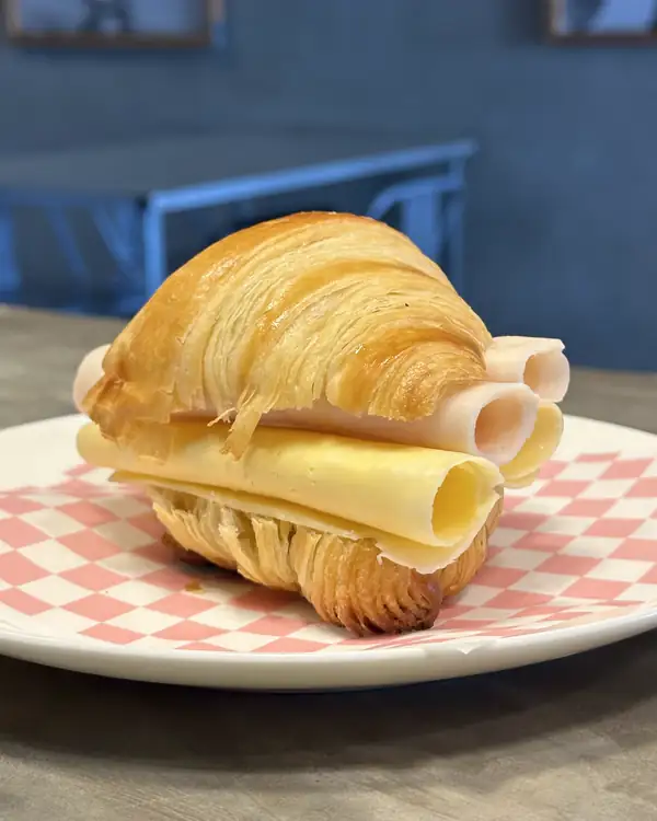 Croissant relleno en un plato de cuadros rosados