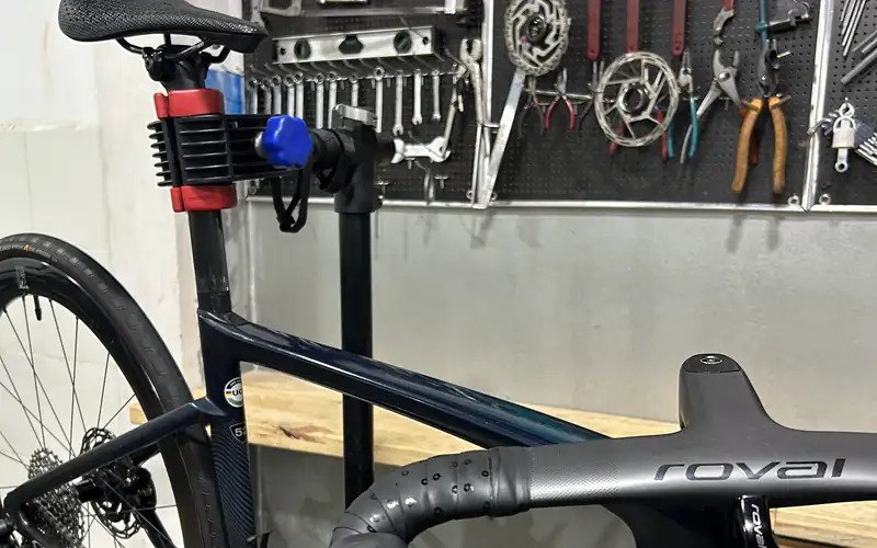 Bicicleta de ruta en el soporte del taller de PEDALiCAFÉ, frente a la pared de herramientas